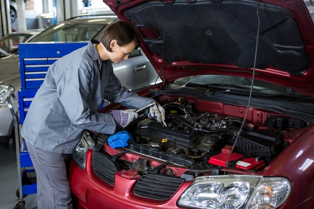 Weibliche Mechaniker den Ölstand in einem Automotor Überprüfung