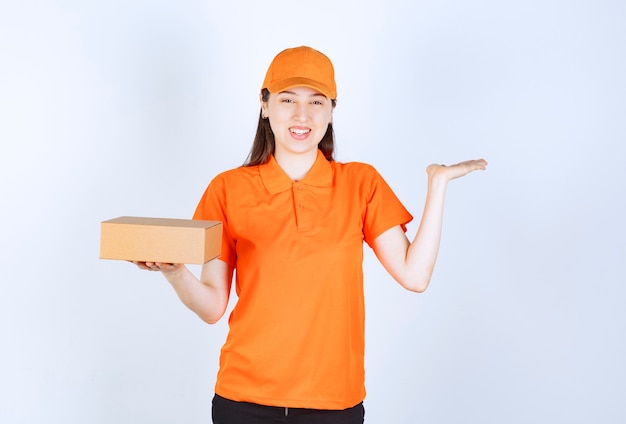 Weibliche Servicemitarbeiterin in orangefarbenem Dresscode, die einen Karton hält