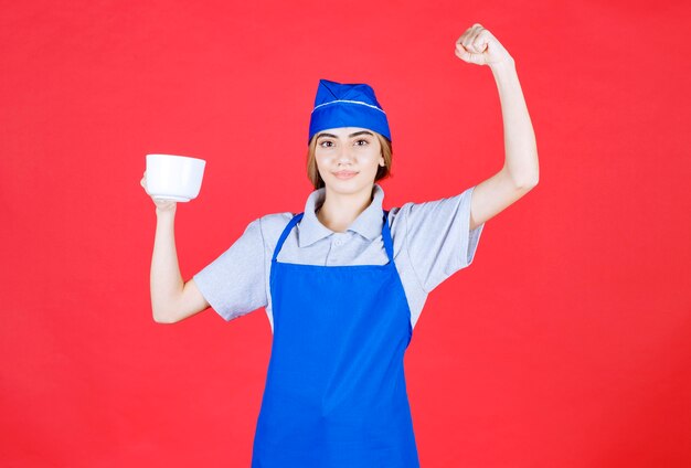 Weiblicher Barista, der eine weiße große Tasse hält und sich mächtig fühlt