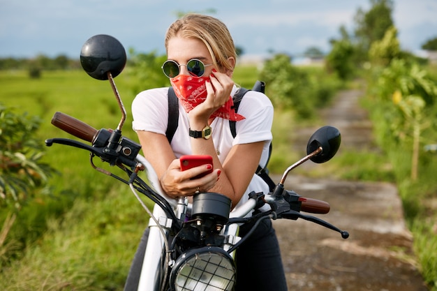 Weiblicher Biker, der neben Motorrad sitzt