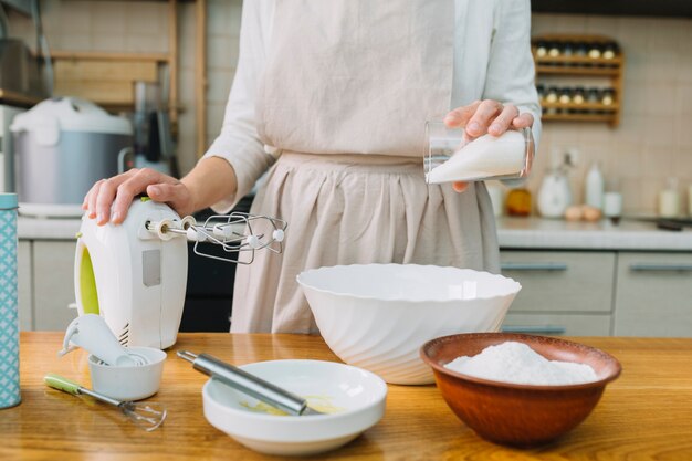 Weiblicher Chef, der Torte in der Küche mit Bestandteilen auf Tabelle vorbereitet