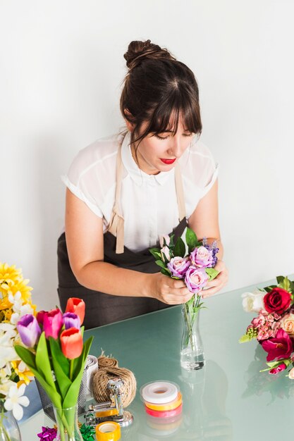 Weiblicher Florist, der Blumen in Vase einsetzt