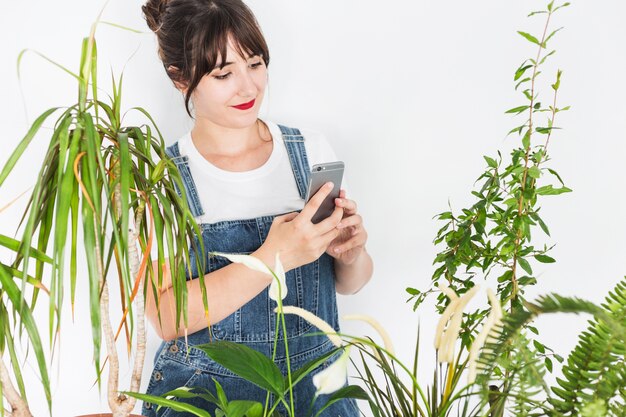 Weiblicher Florist, der Mobiltelefon nahe Anlagen verwendet