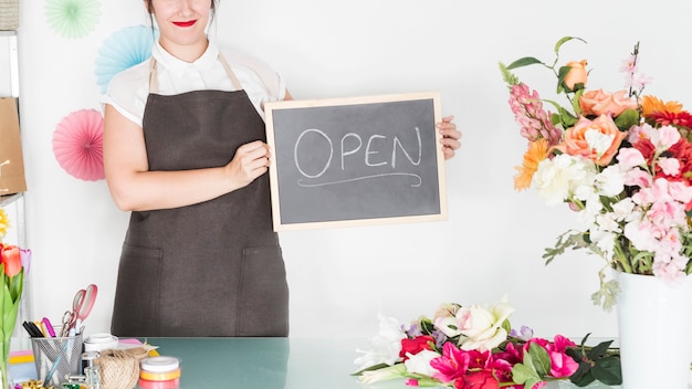 Weiblicher Florist, der Schiefer mit offenem Wort im Blumenshop hält