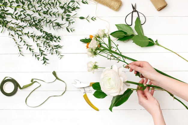 Weiblicher Florist, der schönen Blumenstrauß am Blumenladen macht