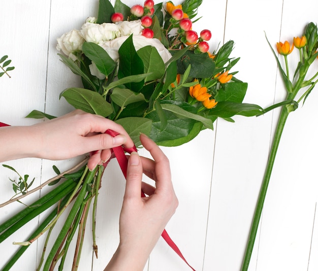 Weiblicher Florist, der schönen Blumenstrauß am Blumenladen macht