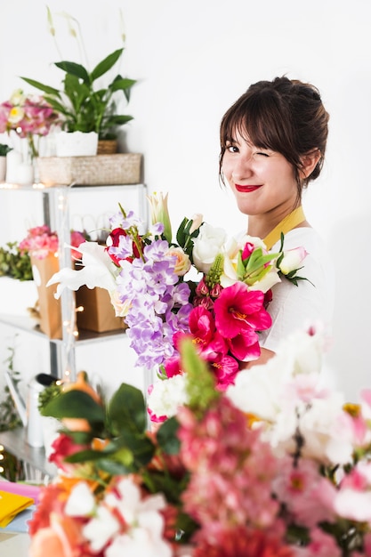 Weiblicher Florist mit dem Blumenstrauß, der im Blumenshop blinzelt