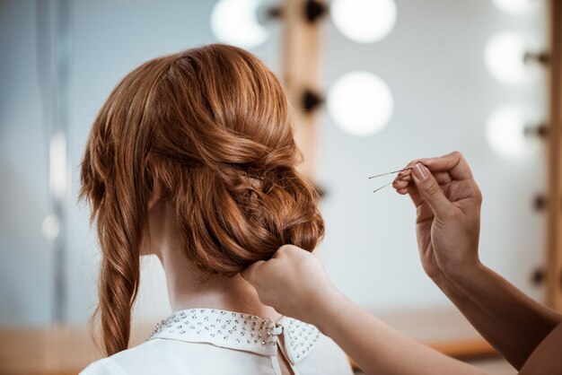 Weiblicher Friseur, der Frisur zu rothaariger Frau im Schönheitssalon macht