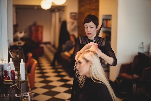 Weiblicher Friseur, der Kundenhaar stylt