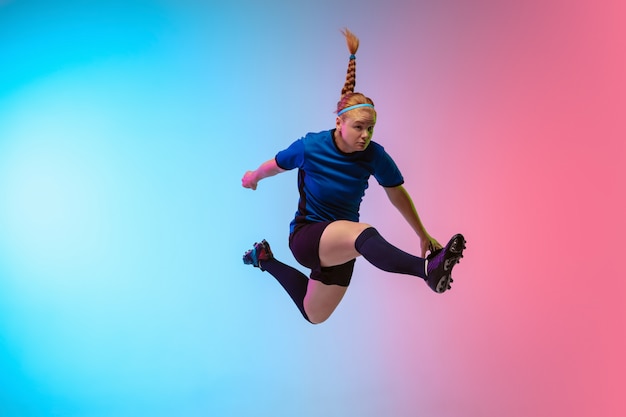 Weiblicher Fußball, Fußballspielertraining in Aktion lokalisiert auf Gradientenstudiohintergrund im Neonlicht