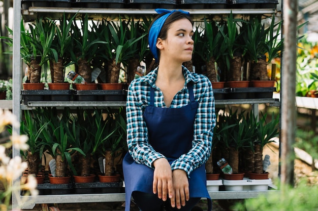 Kostenloses Foto weiblicher gärtner, der vor topfpflanzen sitzt