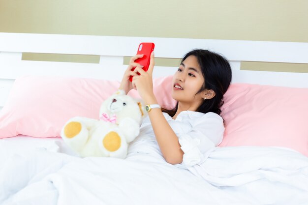Weiblicher Gebrauch Smartphone des Jugendlichen auf dem Bett