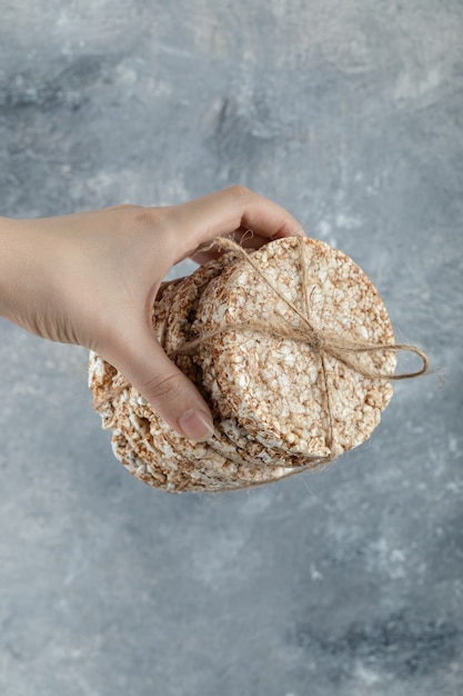 Weiblicher Handhaltestapel von Reiskuchen auf Marmoroberfläche