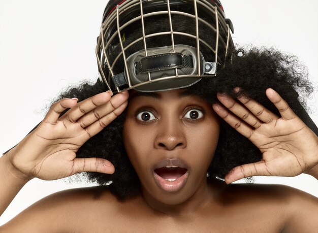 Weiblicher Hockeyspieler schließen Helm und Maske über weißer Wand. Afroamerikanermodell