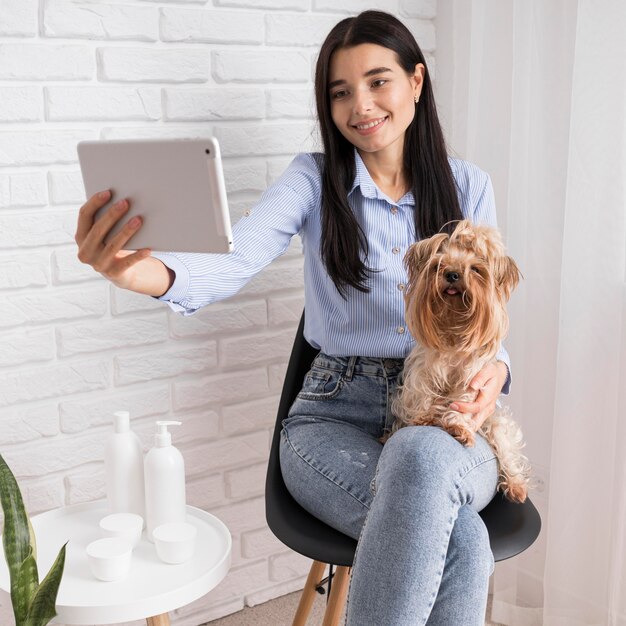 Weiblicher Influencer zu Hause mit Hund und Tablette