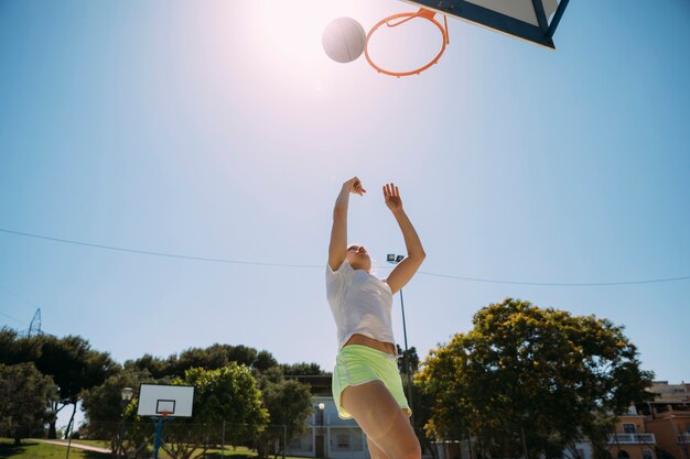 Weiblicher jugendlich Student, der Basketball am sportsground spielt