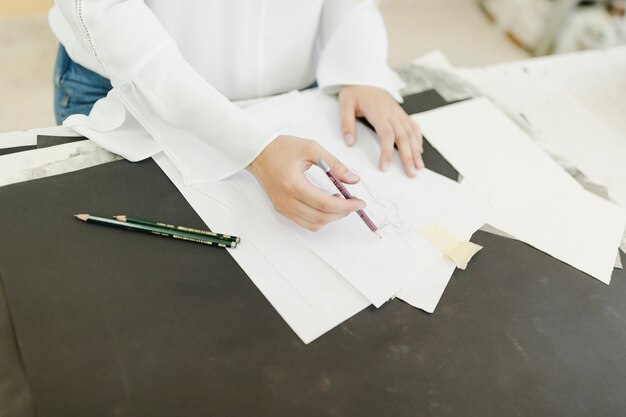 Weiblicher Künstler, der auf Weißbuch mit Bleistift auf Tabelle skizziert
