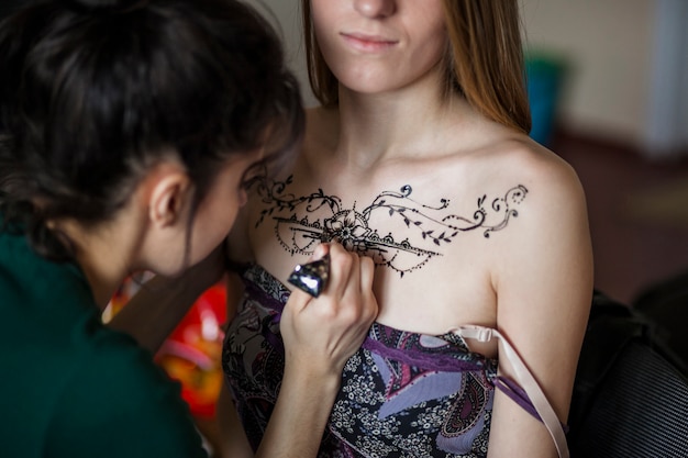 Weiblicher Künstler, der die mehndi Tätowierung auf dem Kasten der Frau zeichnet