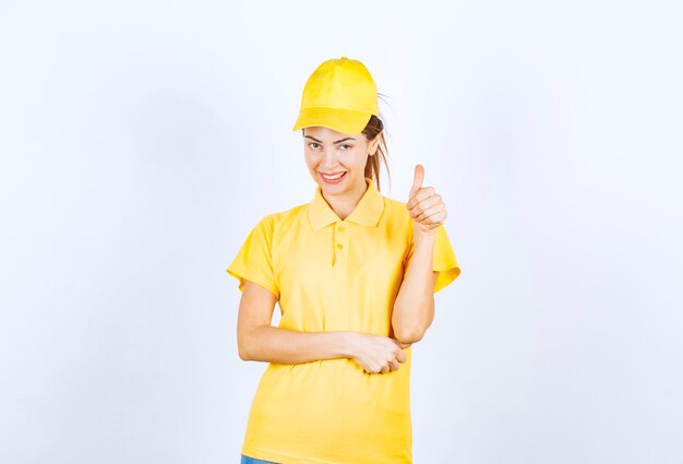 Weiblicher Kurier in gelber Uniform, die Freudenhandzeichen zeigt.