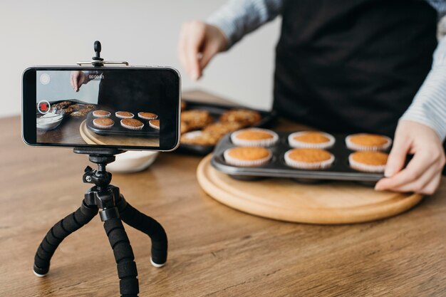 Weiblicher Lebensmittelblogger, der mit Smartphone zu Hause beim Kochen strömt