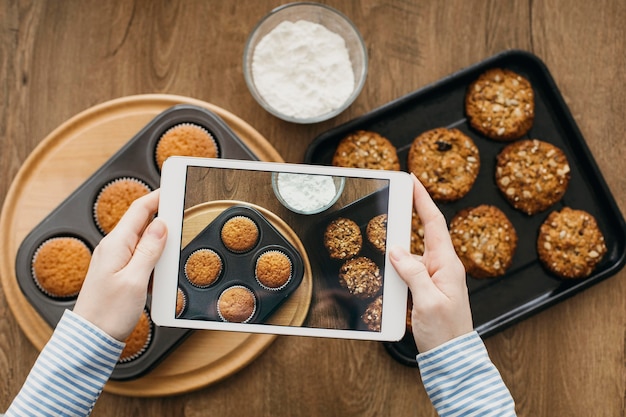 Weiblicher Lebensmittelblogger, der mit Tablette zu Hause beim Kochen strömt