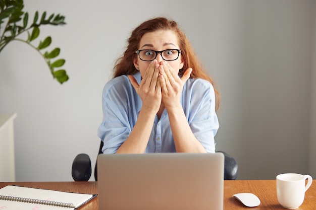 Weiblicher Manager, der am Bürotisch sitzt und mit überraschtem Ausdruck schaut