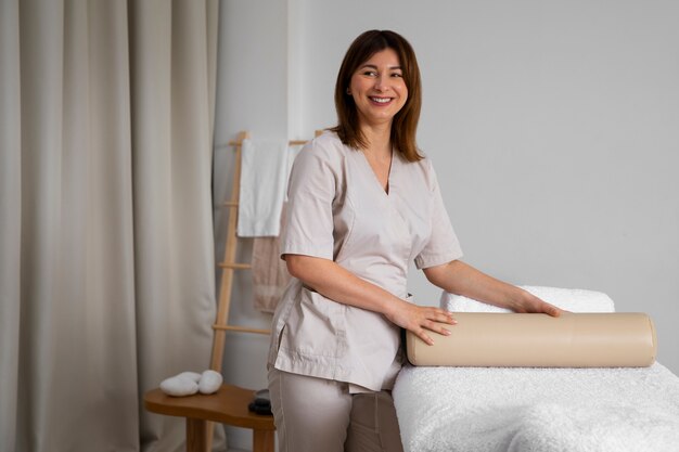 Weiblicher Masseur bereitet Bett für Massagesitzung vor