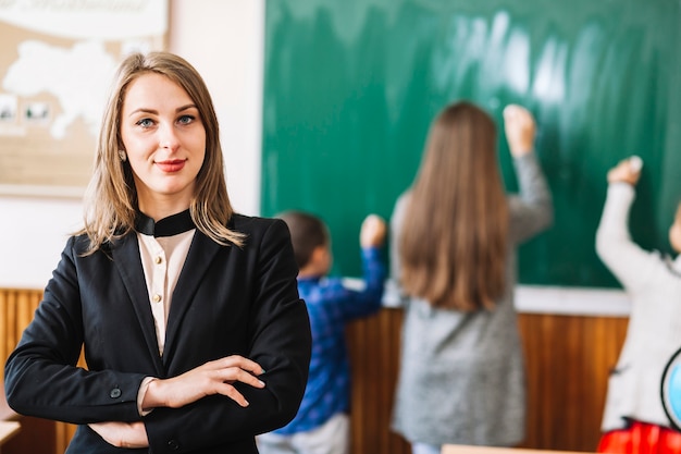 Weiblicher Schullehrer auf Hintergrund der Tafel und der Studenten