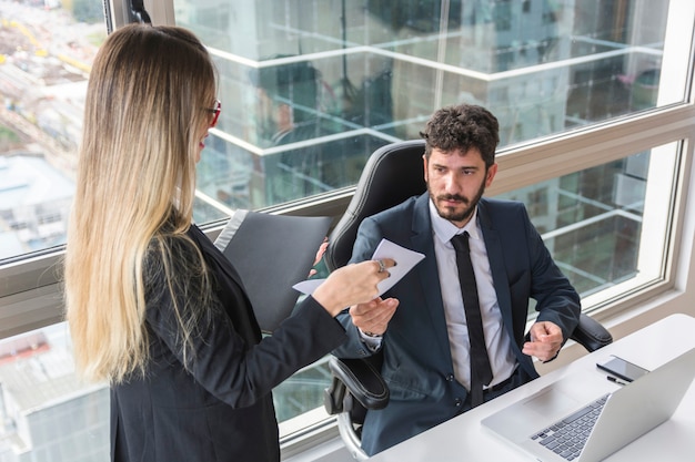 Weiblicher Sekretär, der dem männlichen Manager Dokument am Arbeitsplatz gibt