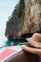 Kostenloses Foto weiblicher tourist, der auf bootsreise nahe der klippe sich lehnt