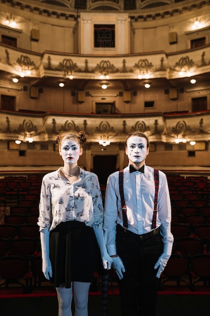 Weiblicher und männlicher Pantomimekünstler, der auf Stadium im Auditorium steht