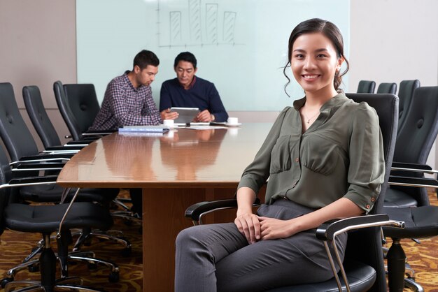 Weiblicher Unternehmensleiter, der am Schreibtisch mit ihren Kollegen arbeiten an der digitalen Auflage im Hintergrund sitzt