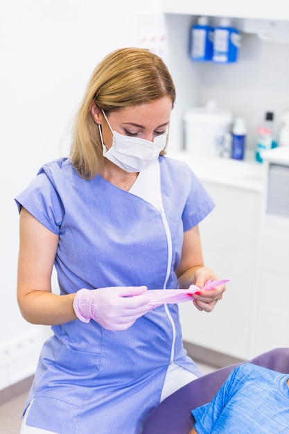 Weiblicher Zahnarzt, der rosa Handschuhe in der Klinik trägt