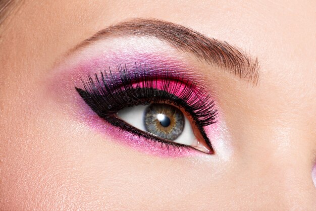 Weibliches Auge der Nahaufnahme mit hellem rosa Make-up der schönen Mode