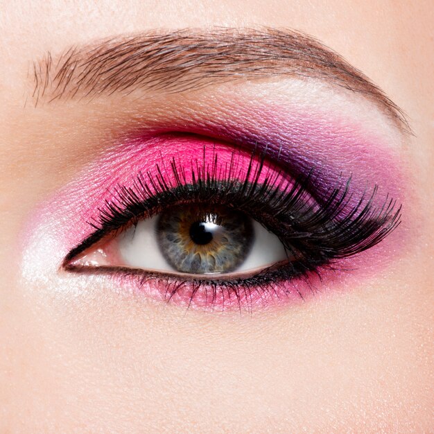 Weibliches Auge der Nahaufnahme mit hellem rosa Make-up der schönen Mode