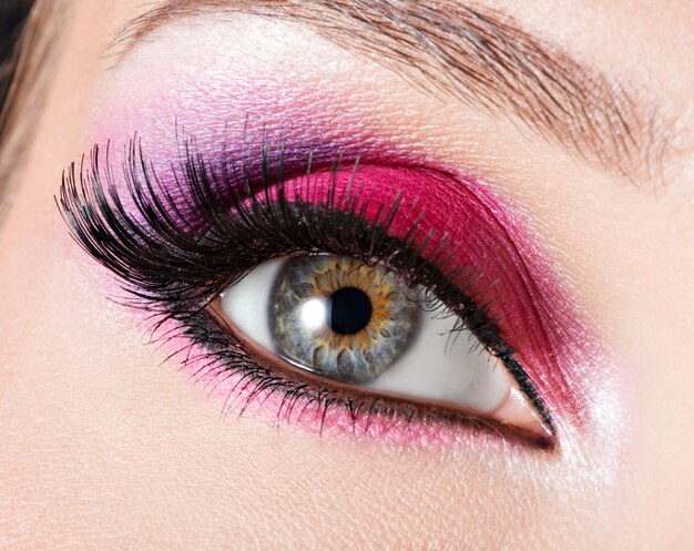 Weibliches Auge der Nahaufnahme mit hellem rosa Make-up der schönen Mode