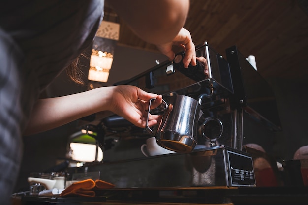 Weibliches barista bereitet Espresso von der Kaffeemaschine im cafÃ © zu