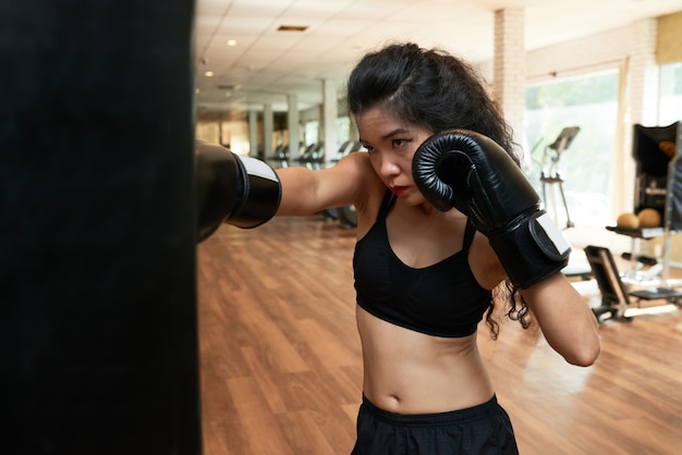 Weibliches Boxertraining in der Turnhalle in den Boxhandschuhen