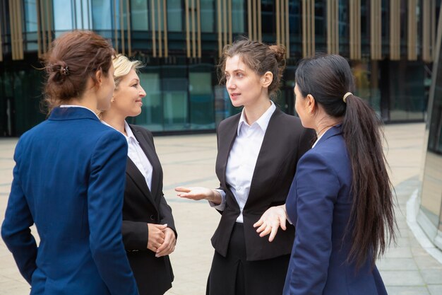 Weibliches Geschäftsteam, das Projekt im Freien bespricht. Geschäftsfrauen tragen Anzüge, die zusammen in der Stadt stehen und sprechen. Kommunikations- und Teamwork-Konzept