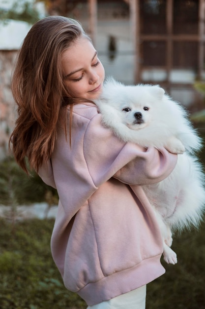 Weibliches Kind, das ihren flauschigen Hund umarmt