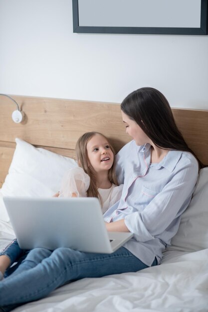 Weibliches Kind und ihre Mutter sitzen im Schlafzimmer