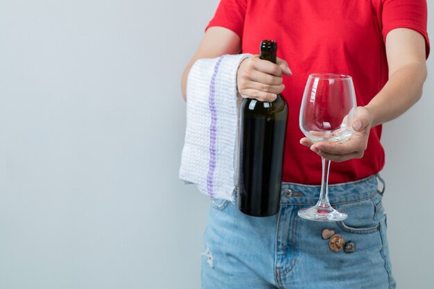 Weibliches Modell im roten Hemd, das eine Flasche Wein mit Glas hält.