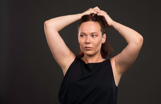 Weibliches Modell im schwarzen Hemd, das Haare sammelt.