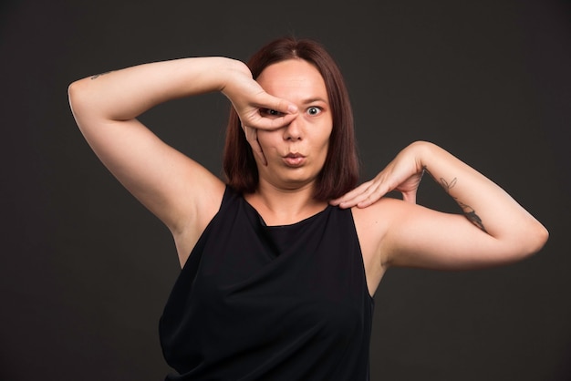 Weibliches modell im schwarzen hemd, das unheimliche pose macht.