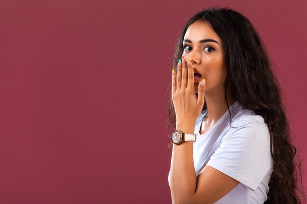 Weibliches Modell macht überraschtes Gesicht auf rosa Wand