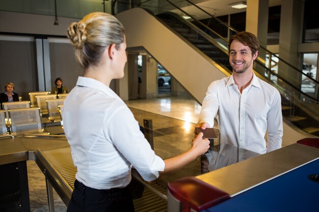 Weibliches Personal, das am Check-in-Schalter eine Bordkarte gibt