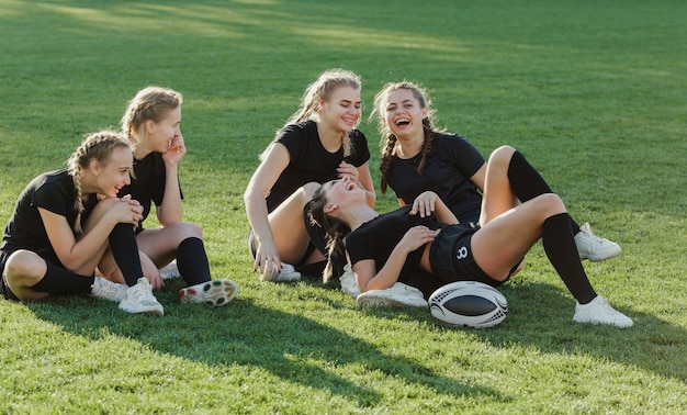 Kostenloses Foto weibliches rugbyteam, das auf gras sitzt