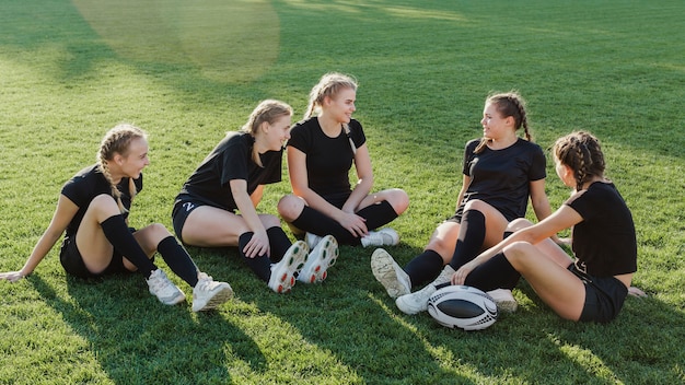 Weibliches Sportteam, das auf Gras sitzt