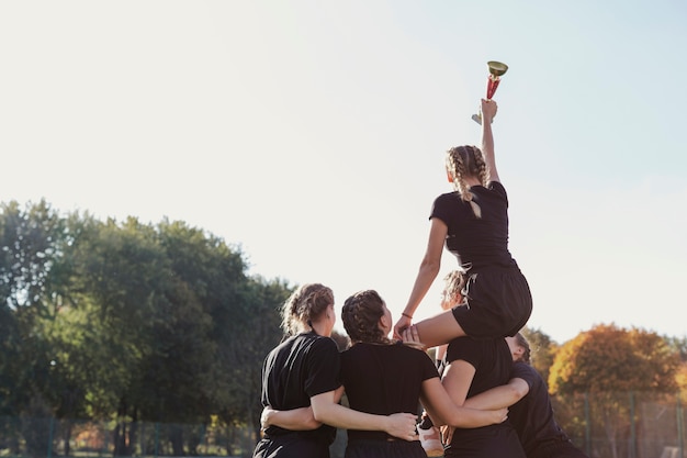 Weibliches Team der hinteren Ansicht, das eine Trophäe gewinnt