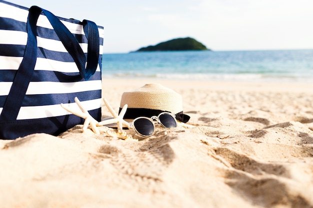 Weibliches Zubehör und Tasche am Strand